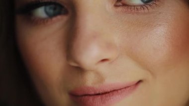 Mavi gözlü kadının yakın plan çekimi. Gün boyu makyajlı gülüşü. Kameraya bak.