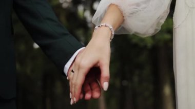 Düğün çifti parkta el ele tutuşuyor. Yavaş çekim. Kafkas romantizmi kutlaması. Sevgililer günü gelin damat aile yüzüğünü seviyor.