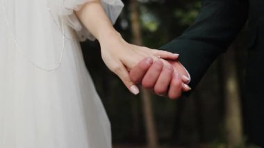 Yakın düğün çifti parkta el ele tutuşuyor Kafkas romantizmi kutlaması Sevgililer Günü damat damat aile yüzüğünü seviyor kadın evliliğini ağır çekimde