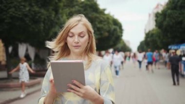 Güzel iş kadını tablet bilgisayar kullanır. Şehir merkezinde yürür. Çekici teknoloji, internet.