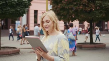 Orta yaşlı sarışın kadın tablet bilgisayar kullanıyor şehir merkezindeki çekici teknoloji internet genç dijital iş ekranı akıllı bir dokunuş yavaş çekime bakıyor