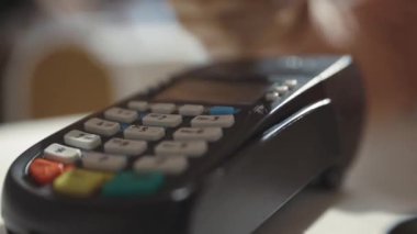 Kablosuz para transferi. Güneşli bir günde ödeme terminaline kredi kartı kullanan bir kız güzel bir kafede sipariş veriyor. NFC teknolojisi.