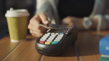NEW YORK - 15 Haziran 2019: Çıkış ve kablosuz para transferi için pozisyon okuyucularına kredi kartı kullanan bir kadının yakın çekimi. Kredi kartı ödemesi. Açık hava görünümü.
