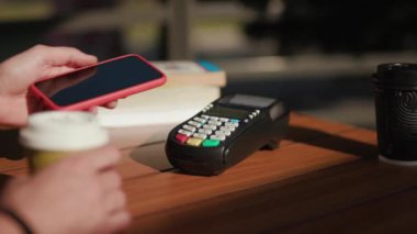 Güneş ışığında çalışan adam NFC teknolojisiyle ödeme yapıyor. Kafede telefon kartı başvurusu. Dijital elektronik kablosuz finansal mobil terminal aktarımı.