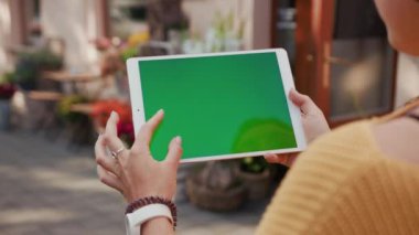 Dijital tablet açık hava krom anahtar yeşil ekran kullanan bir kadının yakın çekimi. Modern teknoloji ve insanlar.