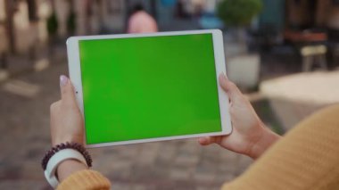 Kafkas kadının elinde yatay beyaz tablet krom anahtar boş yeşil ekran iş uygulaması var..