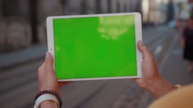 Genç bir kadın şehir planında krom anahtar uygulama şablonuyla modern tablet bilgisayarını gösteriyor. Yakın plan..