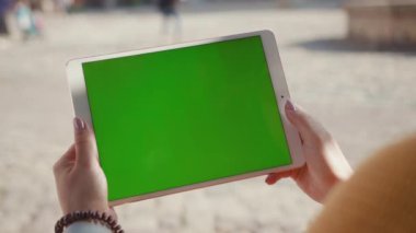 Modern bir cihazla caddede duran yatay yeşil ekran maket tablet bilgisayarı gösteren kadın.