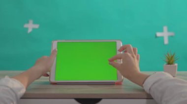 NEW YORK - 5 Nisan 2018: Yatay tablet dijital maket model yeşil ekran cihazı kullanan yakın plan kadın yeşil arka planda izole edildi.