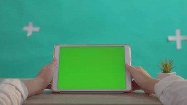 NEW YORK - 5 Nisan 2018: Ahşap masa yakın plan yeşil ekran krom iş uygulaması gösteren beyaz modern tableti tutan kadın eller.