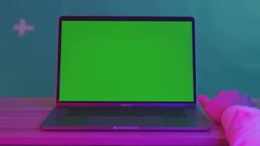 NEW YORK - 5 Nisan 2018: Laptop klavyesinde yazı yazan endişeli genç adam yeşil arka plandaki ahşap masaya endişeyle tıklıyor.
