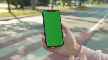 NEW YORK - 5 Nisan 2018: Arka plandaki yaya geçidi otomobili internet teknolojisi şirketinin yavaş çekim mesajı üzerinde yeşil ekranlı bir kadının el ele tutuşması ve telefona dokunması