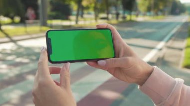 NEW YORK - 5 Nisan 2018: Arka plandaki yaya geçidi otomobili internet teknolojisi şirketinin yavaş çekim mesajı üzerine kadın el ele tutuşup telefona yatay yeşil ekranla dokunmak