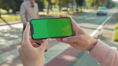 NEW YORK - 5 Nisan 2018: Arka plandaki yaya geçidi otomobili internet teknolojisi şirketinin yavaş çekim mesajında genç kadın el ele tutuşup telefona dokunuyor