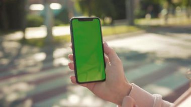 NEW YORK - 5 Nisan 2018: Sokakta arka planda yeşil ekranlı el ele tutuşan ve telefona dokunan genç kadın yaya geçidi otomobili internet teknolojisi mesajı yavaş çekim kapatın