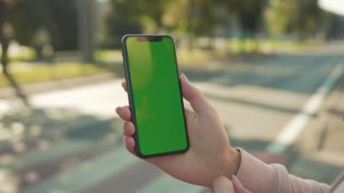 NEW YORK - 5 Nisan 2018: Günbatımında kadın el ele tutuşurken ve yeşil ekranlı telefona dokunurken arka plandaki internet teknolojisi iş mesajında maraton koşan insanlar yavaşlıyor