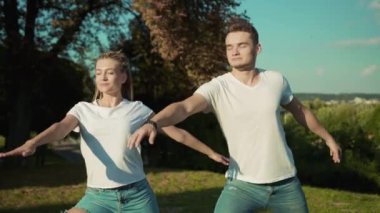 Parkta yoga yapan genç ve sağlıklı bir çift. Etkinlik ve rahatlama kavramı.
