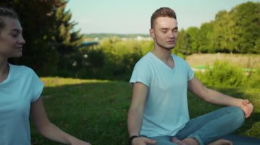 Güzel yeşil Highland Park 'ta yoga kursu sırasında nefes egzersizi yapan birkaç çekici genç..