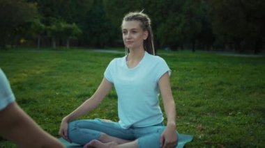 Birkaç genç sporcu yoga pozisyonunda Asana egzersizi yapıyor. Erkek ve kadın yoga eğitimi alıyor. Yaz sabahı harika bir vadide egzersiz yapıyorlar..