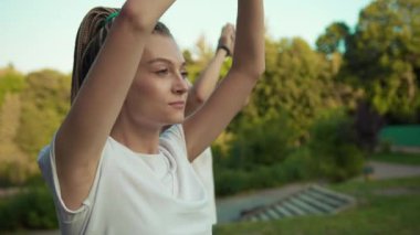 Genç, sağlıklı, beyaz bir çift parkta meditasyon dersinde ruhani egzersizler yapıyor. Yoga gevşemesi.