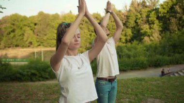 Kafkasyalı hippi kız ve erkek arkadaşı parkta birlikte yoga yaparken dışarıda egzersiz yapıyor. Spor ve sağlık konsepti.