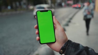 NEW YORK - 5 Nisan 2018: Dikey yeşil ekran arka plan arabası olan akıllı telefonu tutan genç adam şehir dokunmatik ekranlı iş dünyası akşam telefon iletişim cihazı dijital