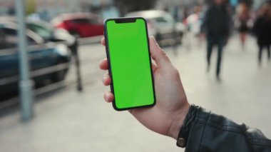 NEW YORK - 5 Nisan 2018: Dikey yeşil ekran arka plan arabası olan akıllı telefonu tutan genç adam şehir dokunmatik ekranlı iş dünyası akşam telefon iletişim cihazı dijital