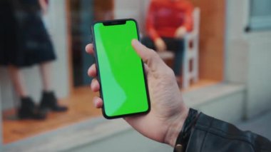 NEW YORK - 5 Nisan 2018: Dikey yeşil ekran arka plan arabası olan akıllı telefonu tutan genç adam şehir dokunmatik ekranlı iş dünyası akşam telefon iletişim cihazı dijital