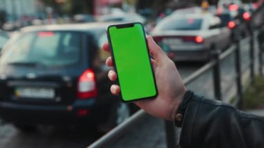 NEW YORK - 5 Nisan 2018: Dikey yeşil ekran arka plan arabalı akıllı telefon tutan genç adam şehir dokunmatik ekran iş dünyası akşamları telefon iletişim cihazı dijital internet