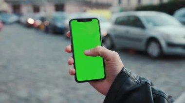 NEW YORK - 5 Nisan 2018: Dikey yeşil ekran arka plan arabalı akıllı telefon tutan genç adam şehir dokunmatik ekran iş dünyası akşamları telefon iletişim cihazı dijital internet