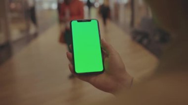 NEW YORK - 19 Mayıs 2019: Alışveriş merkezinin cep telefonu müşteri dijital görüntüleme teknolojisi üzerinde dikey yeşil ekranlı akıllı telefon kullanan ellerini kapat