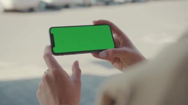 NEW YORK - 19 Mayıs 2019: Elinde telefon tutan kadın ellerini kapat yatay yeşil ekran kullan sokak kaydırma sayfalarında otur İnternet teknolojisi akıllı telefon mesajı cep telefonu yavaş