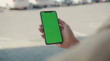 NEW YORK - 19 Mayıs 2019: Güneşli bir günde elinde yeşil ekranlı dikey telefon tutan kadının internet teknolojisi akıllı telefon anahtar mesajı cep telefonuyla sörf sayfalarını kaydırırken görüntüsü