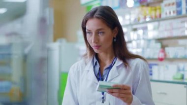 Güzel, neşeli kadın eczane çalışanı kameraya gülümseyen ilaçlar satıyor. Profesyonel kadın portresi. Meslek, sağlık ve tıp kavramı.