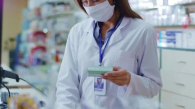 Eczane merkezinde ilaçlarını inceleyen koruyucu maskeli beyaz kadın eczacı. Tıp eğitimi. Coronavirus koruması. Grip..