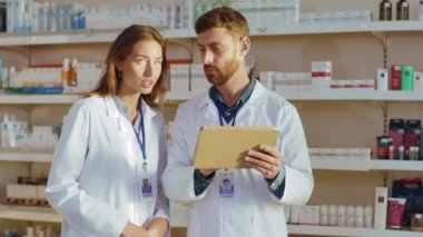 İki Kafkasyalı eczacı, eczanede tıbbi tedavi detaylarını okurken tablet bilgisayar kullanıyor. Eczane. Eczacı..