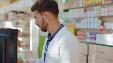 Erkek eczane danışmanı, eczanede müşterilere servis yapan doktor reçeteli ilaçlar satıyor. İlaç, tedavi, sağlık. Meslek ve insanlar.