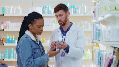NEW YORK - 5 Ekim 2020: Eczanede kadın tıbbi tedavi ürünlerine danışmanlık yapan Apotheracist. Cilt bakımını seçen Afrikalı Amerikalı hasta kız. Eczane kavramı.