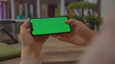 NEW YORK - 19 Mayıs 2019: Home Sitting on Chair 'de yatay yeşil ekranlı Mobile Smartphone tutan bir kadının eli. Akıllı Telefon Teknolojisi. Cep Telefonu Ev Dokunuşu İletisi Görüntüsü
