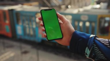 NEW YORK - 19 Mayıs 2019: Dikey yeşil ekran arka plan tramvayı olan telefonu kullanan genç adamı kapat internet krom açık hava cep telefonu akıllı telefonları yavaş dinleme iletişimi