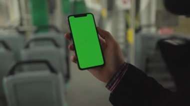 NEW YORK - 19 Mayıs 2019: Eller, arka planda dikey yeşil ekran tramvay koltuğu olan bir cep telefonu kullanır.
