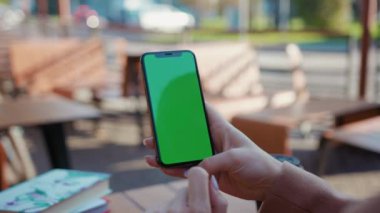 NEW YORK - 5 Nisan 2019: Kafede dikey yeşil ekranlı akıllı telefon kullanan genç eller açık havada yeni teknolojiyi görüntülüyor yavaş çekimde açık hava mesajını kapatın