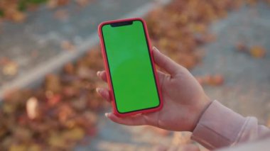 NEW YORK - 5 Nisan 2019: Güneşli bir günde elinde yeşil ekran ile dikey telefon tutan eller internet teknolojisi akıllı telefon krom anahtar mesaj cep telefonunu araklıyor