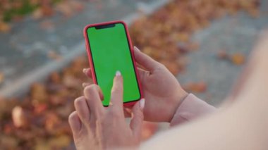 NEW YORK - 5 Nisan 2019: Güneşli bir günde elinde yeşil ekran ile dikey telefon tutan eller internet teknolojisi akıllı telefon krom anahtar mesaj cep telefonunu araklıyor