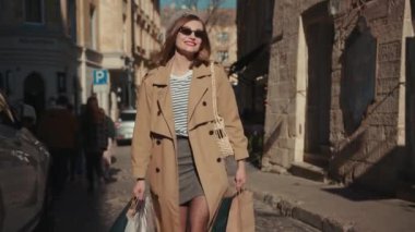 NEW YORK - 5 Nisan 2019: Kırmızı ruj şapkalı, şık ceketli çekici bir kadın güneşli bir günde etrafına bir bak çantalar, alışveriş çantaları şehir kıyafetleri caddesi genç şehir müşterisi moda müşterisi