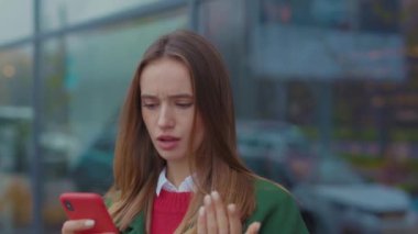 Öfkeli genç bir kadın Noel zamanı şehir merkezinde telefon kullanır. İnternet, mobil, Kafkas, cep telefonu, sokak, şehir, genç, çekici, güzel, yavaş çekim hücresi.