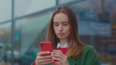 Kapalı yüzlü, üzgün genç kadın Noel zamanı şehir merkezinde telefon kullanıyor. İnternet gezgini, Kafkasyalı cep telefonu, sokak çocuğu, genç, çekici, güzel, yavaş çekim hücresi.