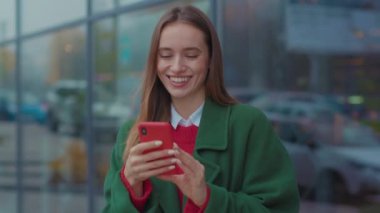 Gülümseyen genç bir kadın Noel zamanı şehir merkezinde telefon kullanıyor mutlu internet gezgini, Kafkas cep telefonu, şehir merkezi genç, çekici, güzel, yavaş çekim hücresi.