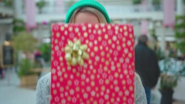 Ciddi ciddi genç kadın, kameraya bak Noel hediyelerini sokak mağazasının önünde tut Noel zamanı çekici bir portre, yavaş çekimde çek.