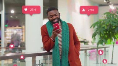 Portre Afro-Amerikan gülümseyen genç adam alışveriş merkezi akıllı telefon kullanıyor yorumcu sayacı gibi sosyal medya simgeleri yazıyorlar blogda hızlı artış blogcusu yavaş çekim blogunu kapatın